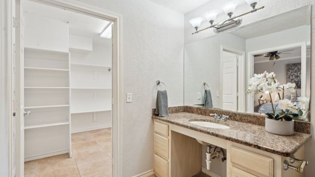 Bathroom with a spacious closet, vanity, tile patterned flooring, and a textured wall | Image 22
