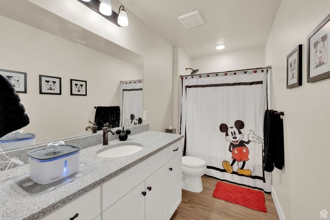 Bathroom featuring wood finished floors, vanity, toilet, and curtained shower | Image 26
