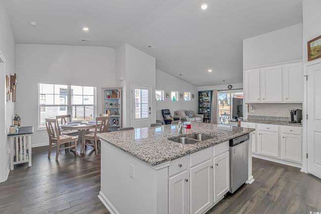 Kitchen with white cabinetry, dishwasher, sink, a kitchen island with sink, and light stone counters | Image 5
