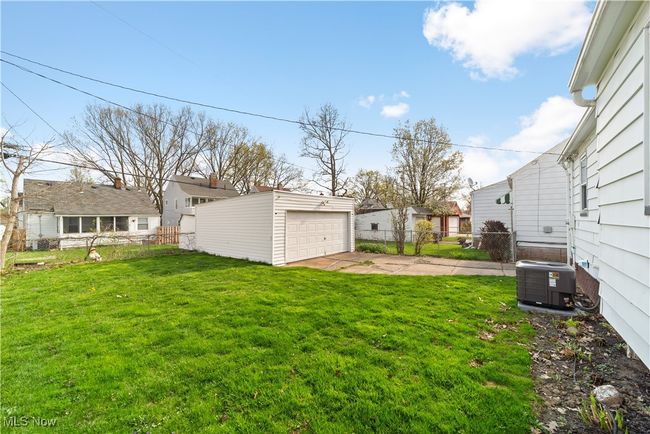 View of yard featuring cooling unit, a residential view, an outbuilding, fence, and a garage | Image 31