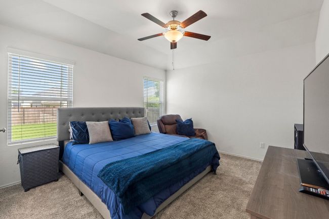 The primary suite with ceiling fan is privately located at the back of the home. | Image 17