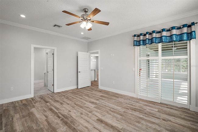 Primary bedroom with crown molding, Planation shutters, en-suite and sliders to the enclosed lanai. | Image 14
