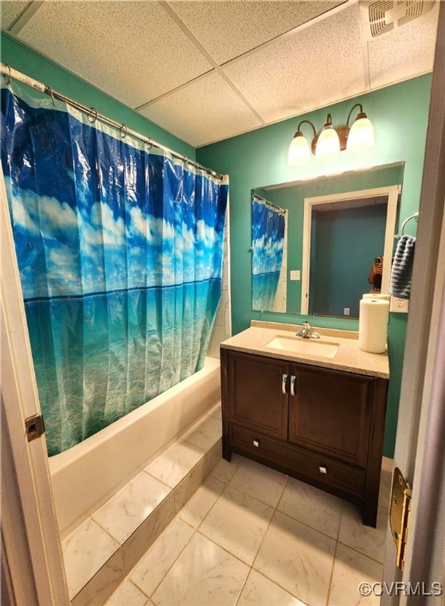 Full bath with marble finish flooring, shower / tub combo, vanity, and a drop ceiling | Image 33