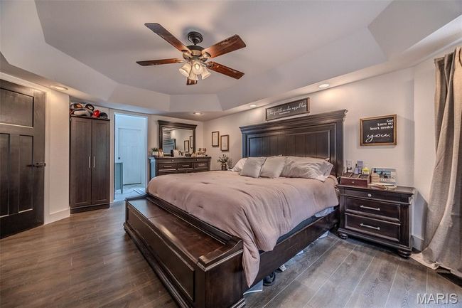 Bedroom featuring a tray ceiling, dark wood finished floors, a ceiling fan, and access to outside | Image 29