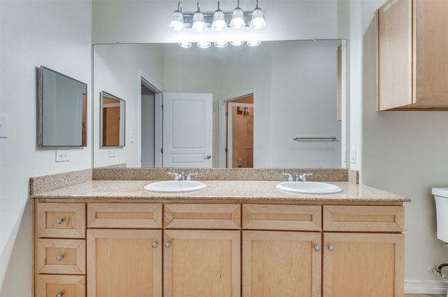 The en suite bath exudes spa-caliber sophistication: dual granite-topped vanities with mounted sinks, a soaking tub shower combination and ample storage. | Image 30