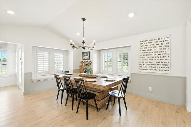 Dining space with a chandelier, light wood-style flooring, recessed lighting, vaulted ceiling, and wainscoting | Image 8