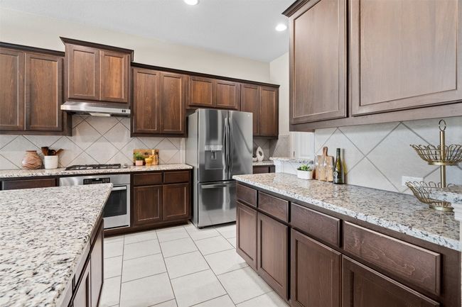 Tall chocolate brown cabinets pair seamlessly with the beautiful granite counters | Image 11