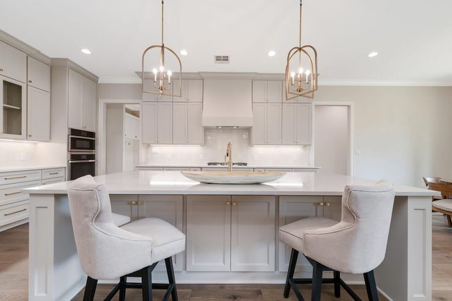 Kitchen featuring a chandelier, ornamental molding, a large island, light countertops, and decorative backsplash | Image 15