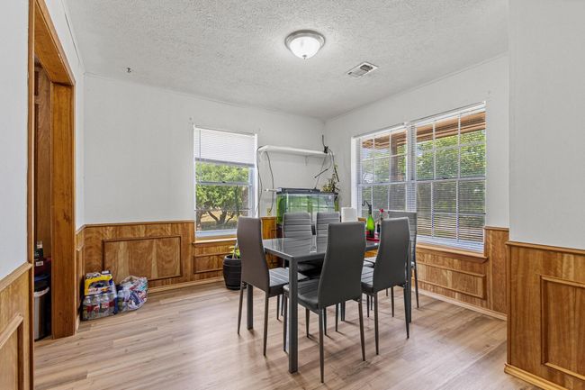 Dining space with a wainscoted wall, wooden walls, plenty of natural light, a textured ceiling, and light wood-style flooring | Image 16