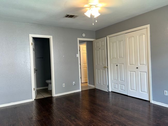 Unfurnished bedroom with wood finished floors, a closet, connected bathroom, and a ceiling fan | Image 11