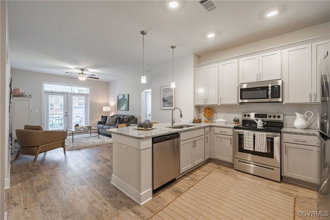 Kitchen featuring tasteful backsplash, light stone counters, a peninsula, appliances with stainless steel finishes, and a sink | Image 25