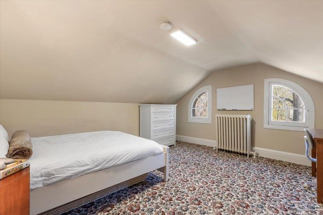Carpeted bedroom with radiator, baseboards, and vaulted ceiling | Image 21