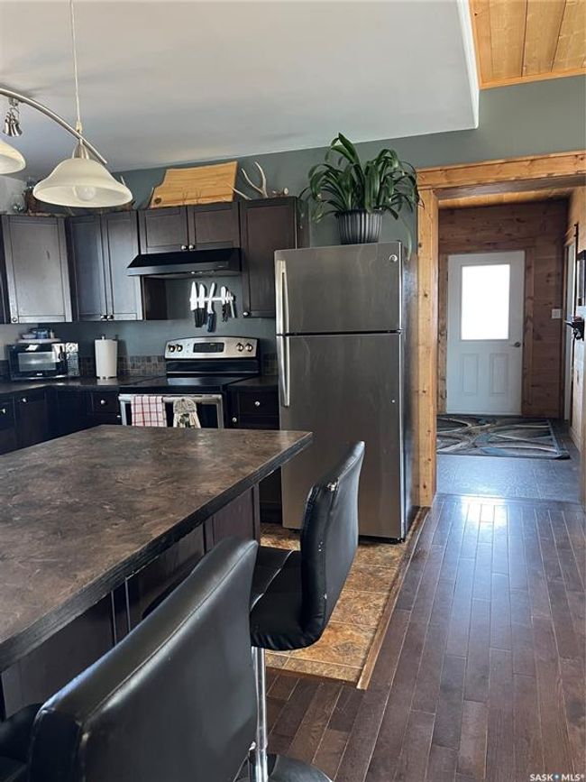 Kitchen with refrigerator, stove, ventilation hood, and dark countertops | Image 11