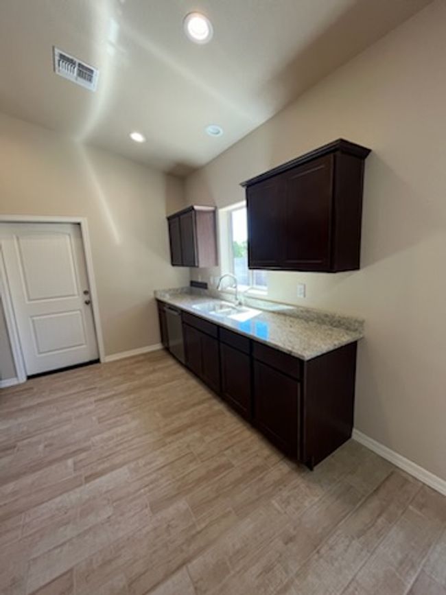 Kitchen featuring a sink, dark brown cabinets, light wood-style flooring, baseboards, and recessed lighting | Image 7