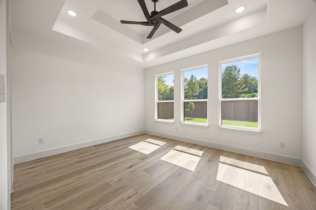 Empty room with a tray ceiling, baseboards, light wood finished floors, a ceiling fan, and recessed lighting | Image 16