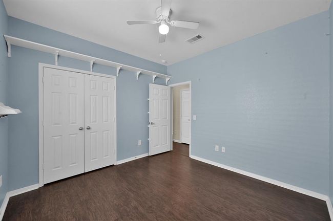 Compact laundry room with a washer and dryer, shelving for storage, and a door leading out. The room has tiled floors and neutral color walls. | Image 26