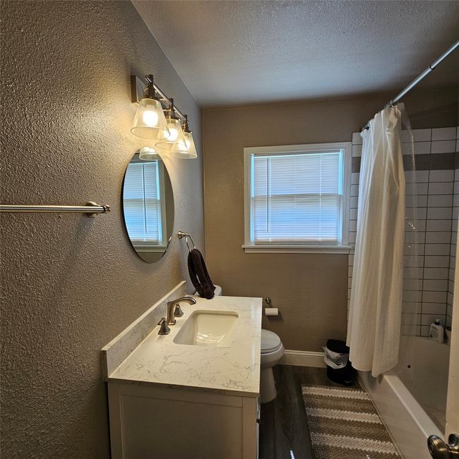 Full bathroom featuring a textured wall, vanity, shower / bath combo. | Image 15