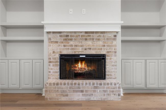 Interior details featuring built in shelves, a brick fireplace, and hardwood / wood-style floors | Image 10