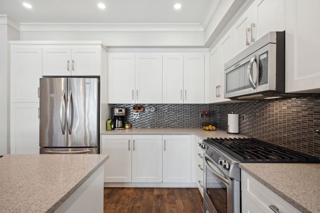Kitchen featuring crown molding, tasteful backsplash, appliances with stainless steel finishes, and dark wood-type flooring | Image 12