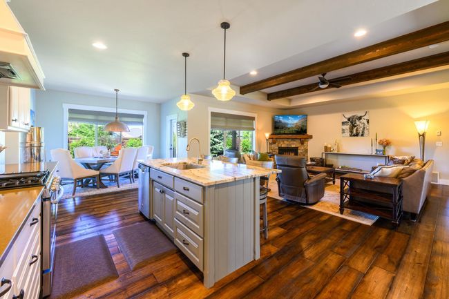 Kitchen featuring a sink, stainless steel appliances, dark wood-type flooring, a stone fireplace, and open floor plan | Image 10
