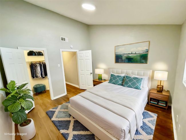 Bedroom featuring a spacious closet, wood finished floors, visible vents, baseboards, and high vaulted ceiling | Image 12