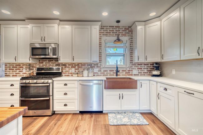 Kitchen featuring stainless steel appliances, hanging light fixtures, backsplash, light wood finished floors, and recessed lighting | Image 8