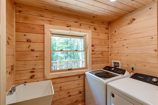 Laundry room featuring washer and clothes dryer, wooden walls, and wood ceiling | Image 33