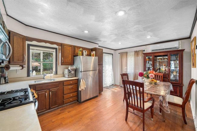 Kitchen featuring freestanding refrigerator, an AC wall unit, a sink, light countertops, and light wood-type flooring | Image 6