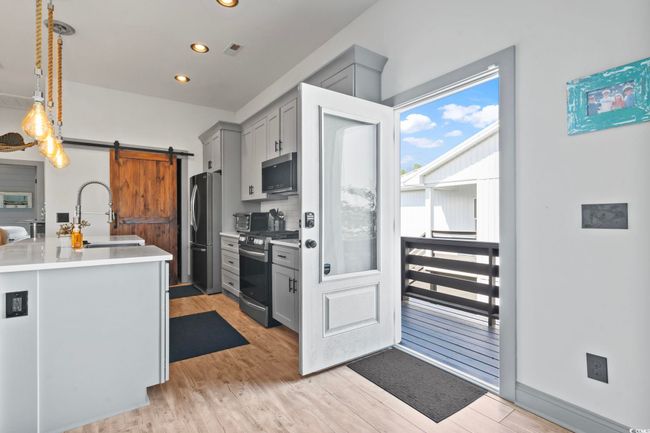 Kitchen featuring a barn door, a sink, gray cabinets, stainless steel appliances, and light wood-style flooring | Image 26