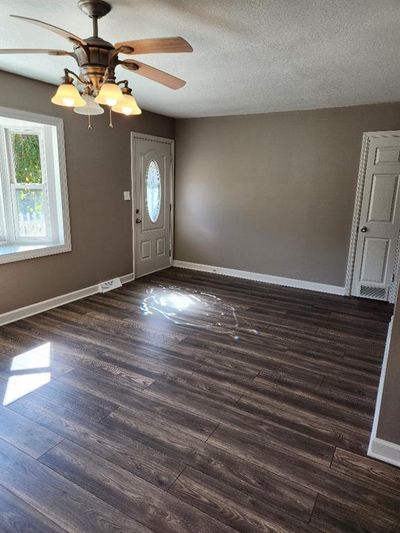 Entrance foyer with a textured ceiling, a healthy amount of sunlight, dark hardwood / wood-style floors, and ceiling fan | Image 2