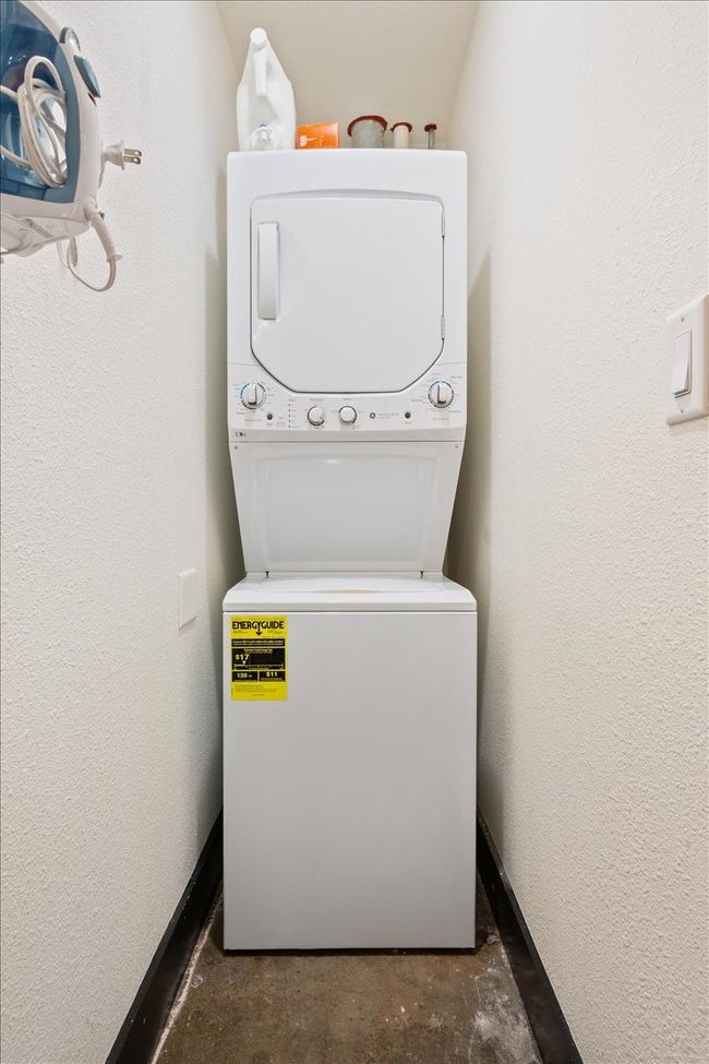 Laundry area with stacked washer and clothes dryer and a textured wall | Image 16