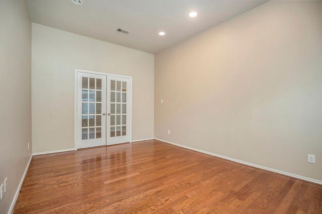 This private home office is set apart with double French doors, recessed lighting, and beautiful wood flooring. Whether you're working from home or need a quiet place to focus, this versatile space offers both comfort and style. | Image 6