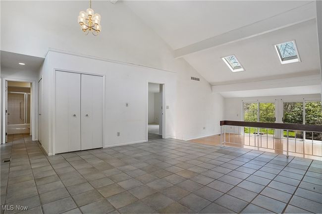 Unfurnished living room featuring high vaulted ceiling, a skylight, a chandelier, beamed ceiling, and baseboards | Image 36