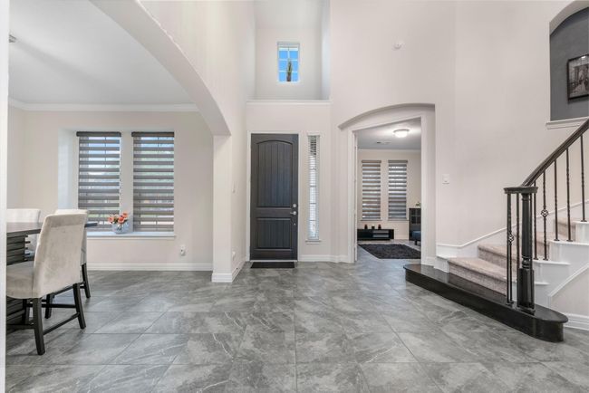 Featuring high ceilings and a modern design.The space is bright, with large windows and elegant gray tiles. An arched doorway leads to a cozy living area, and a stylish staircase with wrought iron railing adds a touch of sophistication | Image 4
