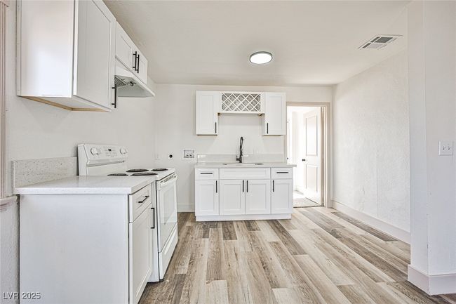 Kitchen featuring white range with electric stovetop, light wood-type flooring, white cabinets, and light countertops | Image 11