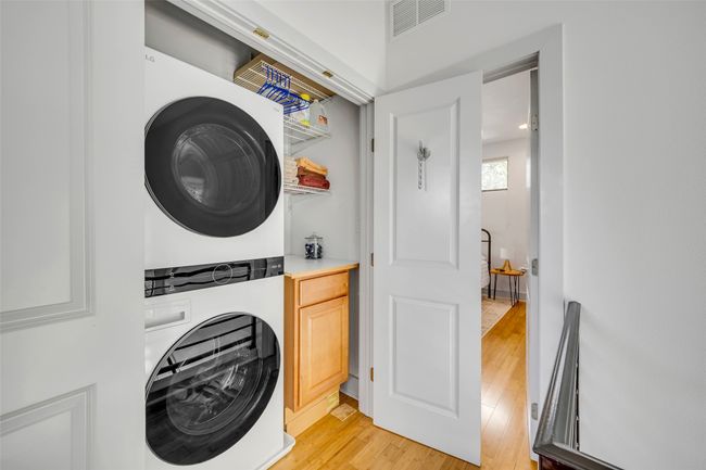 Clothes washing area with light hardwood / wood-style flooring and stacked washer and clothes dryer | Image 29