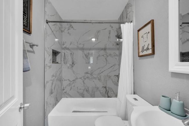 Bathroom with a textured wall, toilet, and shower / bathtub combination with curtain | Image 24