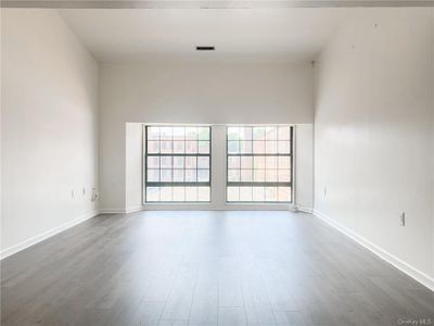 Empty room with a towering ceiling and wood-type flooring | Image 1