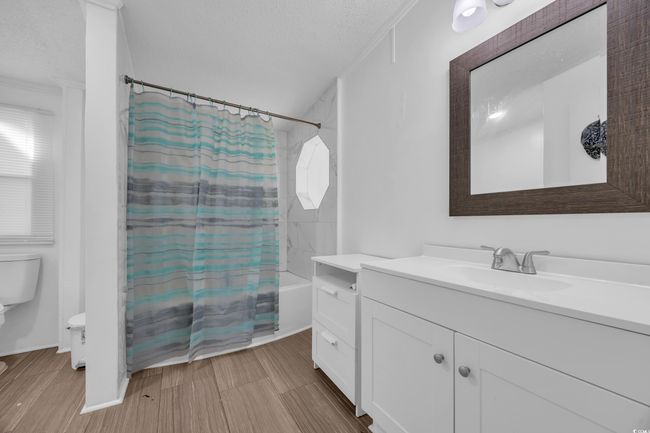 Full bath with toilet, vanity, shower / bath combination with curtain, and a textured ceiling | Image 16