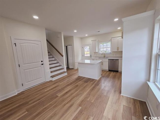 Kitchen featuring a center island, light countertops, white cabinets, a sink, and dishwasher | Image 25