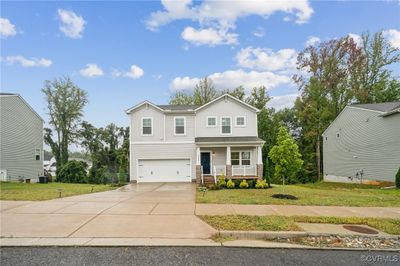 View of front of house featuring a front lawn, covered porch, and a garage | Image 1