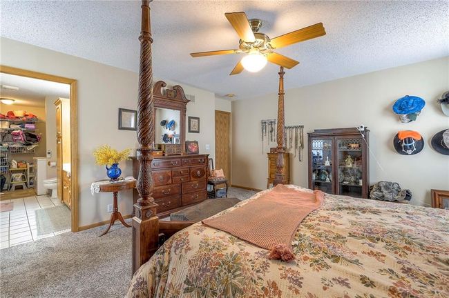 Bedroom with carpet, ceiling fan, a textured ceiling, and connected bathroom | Image 18