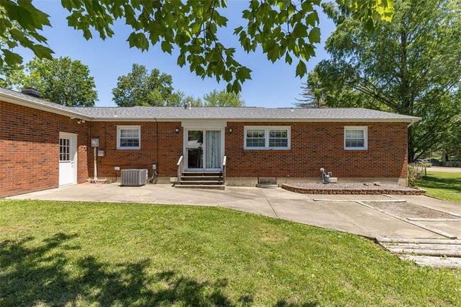 Rear view of property featuring a patio area, entry steps, a yard, and central AC unit | Image 8