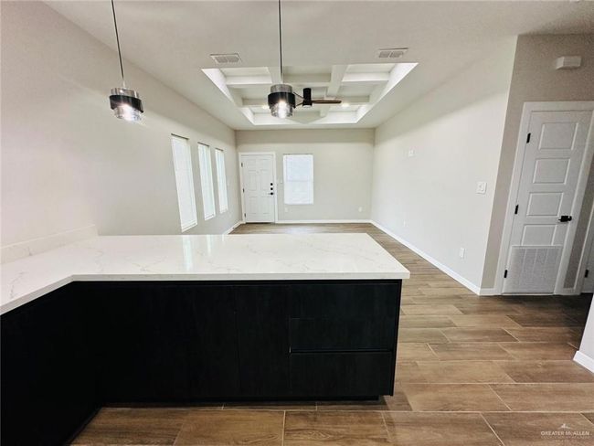 Kitchen with coffered ceiling, a ceiling fan, light wood-style floors, light stone countertops, and open floor plan | Image 5