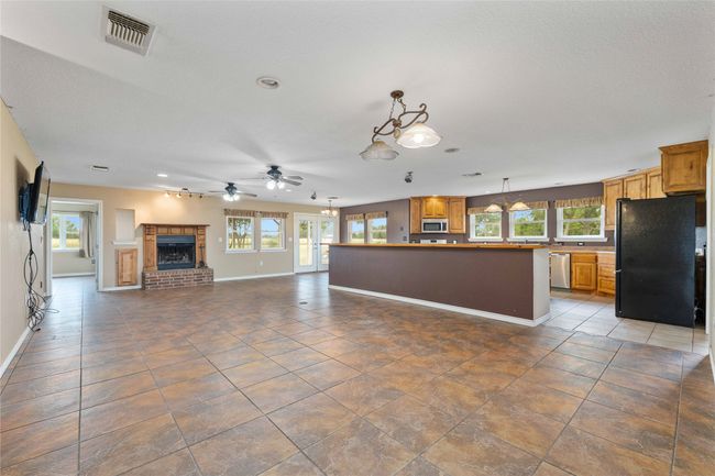 Unfurnished living room featuring a fireplace, a ceiling fan, tile patterned flooring, and recessed lighting | Image 5