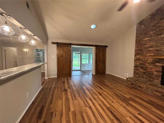 Unfurnished living room featuring a barn door, dark wood-style flooring, and high vaulted ceiling | Image 11