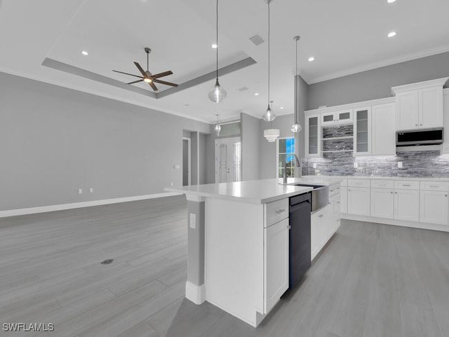 Kitchen with stainless steel microwave, dishwasher, tasteful backsplash, an island with sink, and ceiling fan | Image 14
