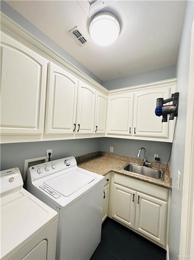 Laundry area featuring cabinet space, separate washer and dryer, and dark tile patterned floors | Image 23