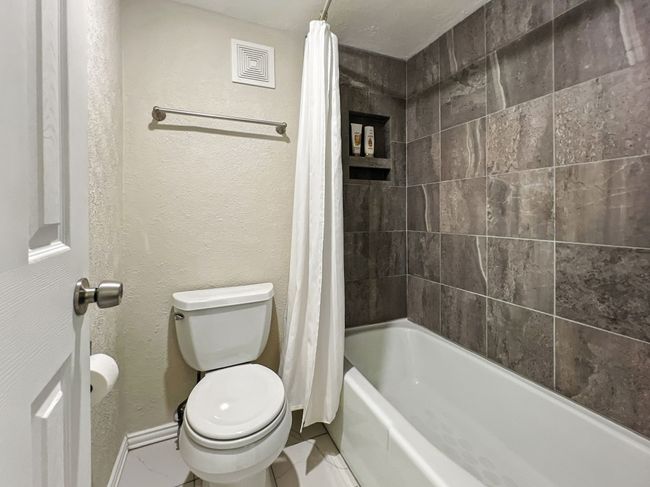 Bathroom with a textured wall and shower / bath combo with shower curtain | Image 9
