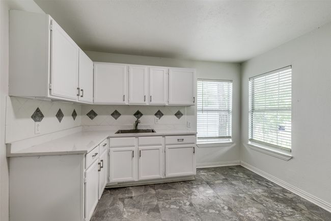 Kitchen with white cabinets and decorative backsplash | Image 11